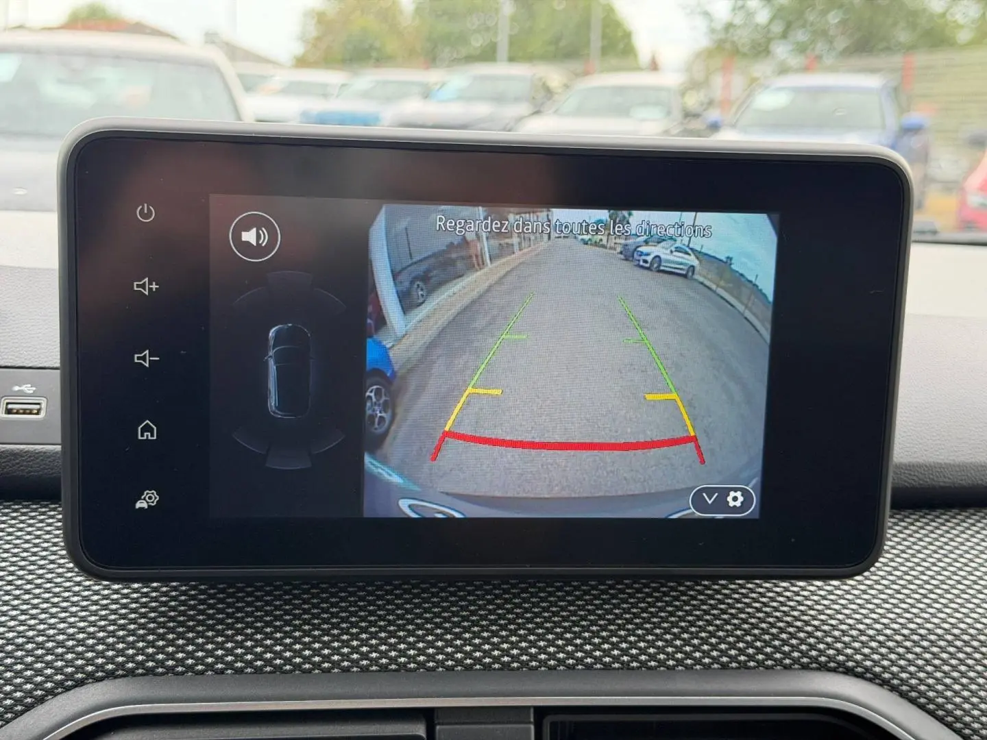 Écran tactile intérieur montrant la caméra de recul d'un Dacia Jogger vert Cèdre, vue arrière en stationnement.