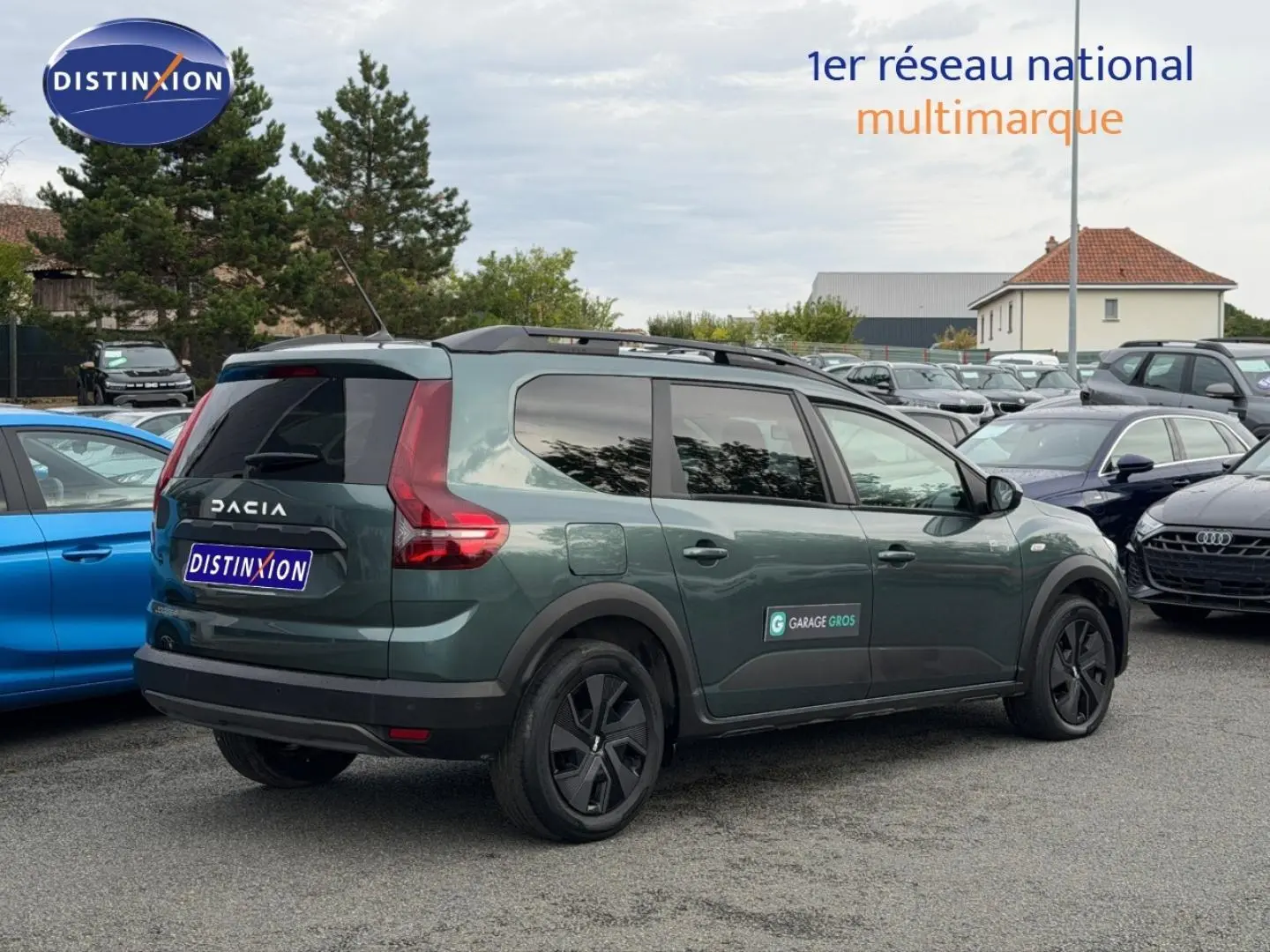 Vue 3/4 arrière droite du Dacia Jogger 2025 vert cèdre métallisé avec barres de toit et vitres surteintées.