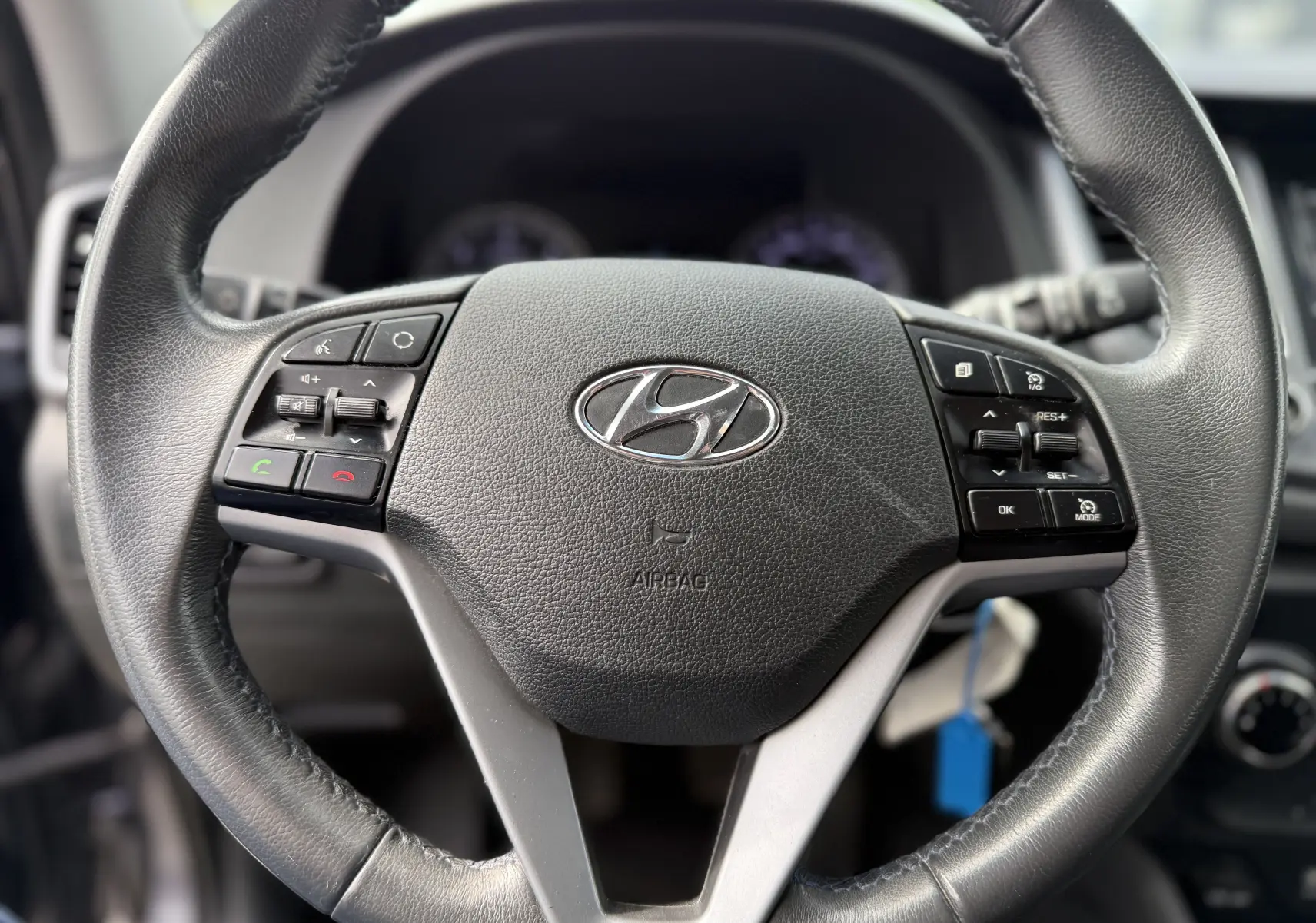 Gros plan sur le volant en cuir noir du Hyundai Tucson 2015 avec commandes intégrées et logo Hyundai central.