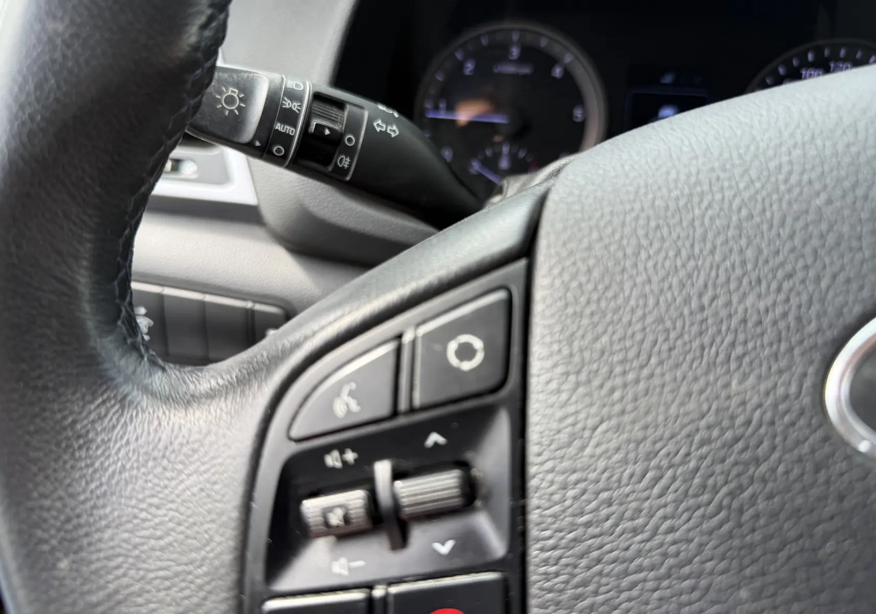 Gros plan sur le volant noir du Hyundai Tucson gris 2015, montrant les commandes audio et téléphone intégrées.