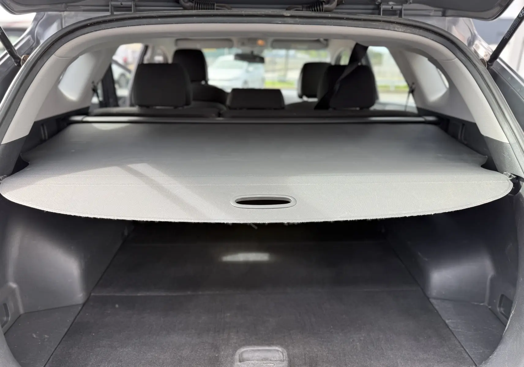 Coffre ouvert d'un Hyundai Tucson gris 2015, vue arrière montrant la plage arrière couvrant le coffre spacieux.