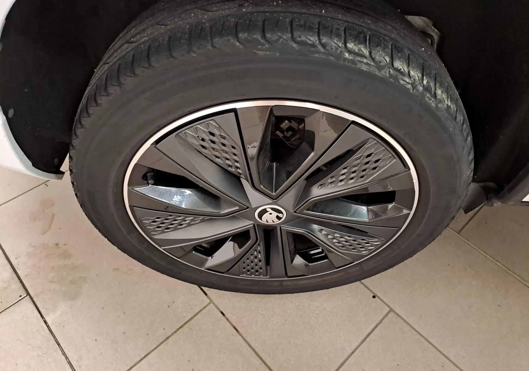 Gros plan sur la roue avant droite du Skoda Karoq 2.0 TDI 116 DSG7 Sportline blanc lune avec jante noire et grise.