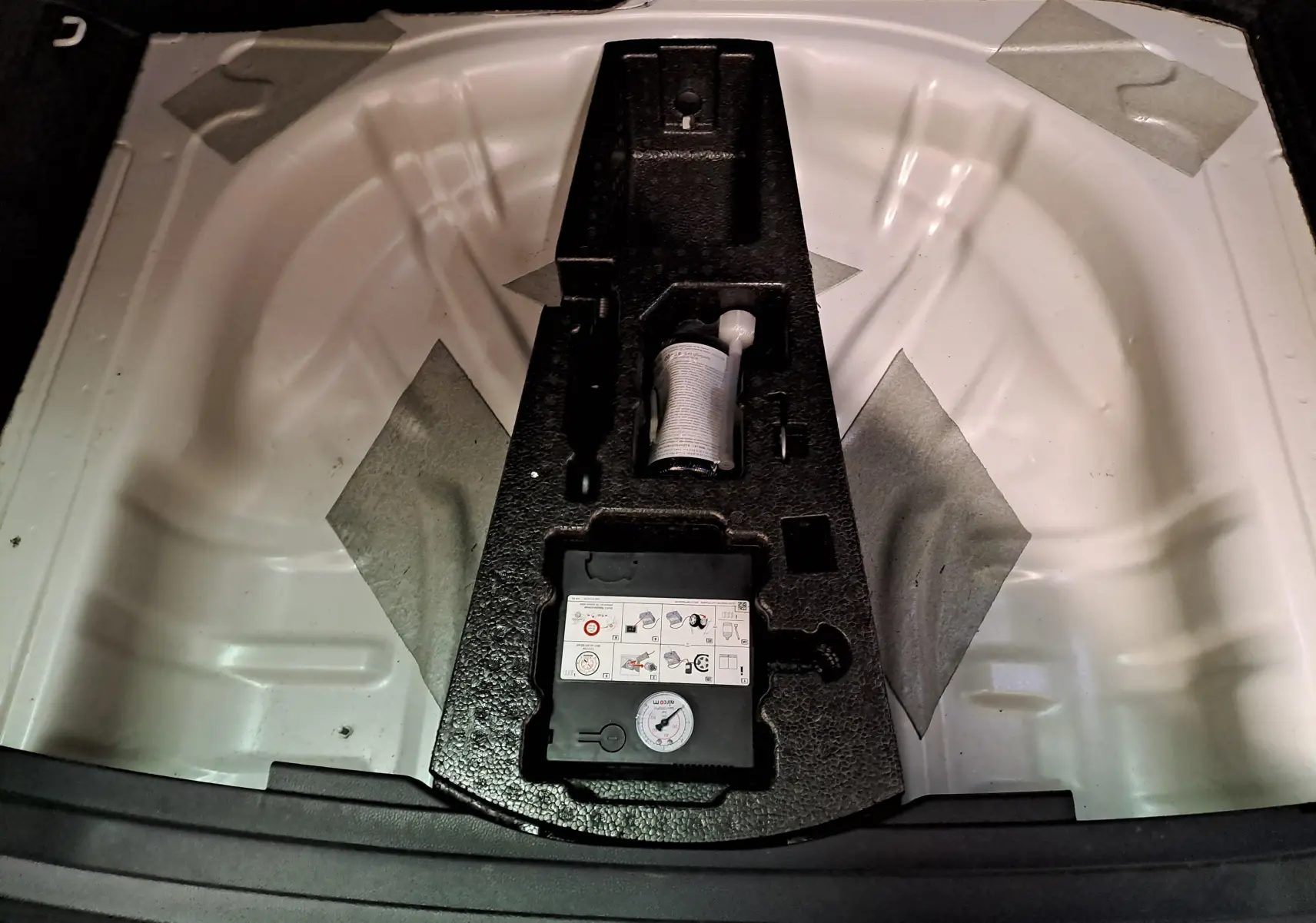 Vue plongeante sur le coffre d’un Skoda Karoq blanc lune 2022, montrant le rangement sous la roue de secours.