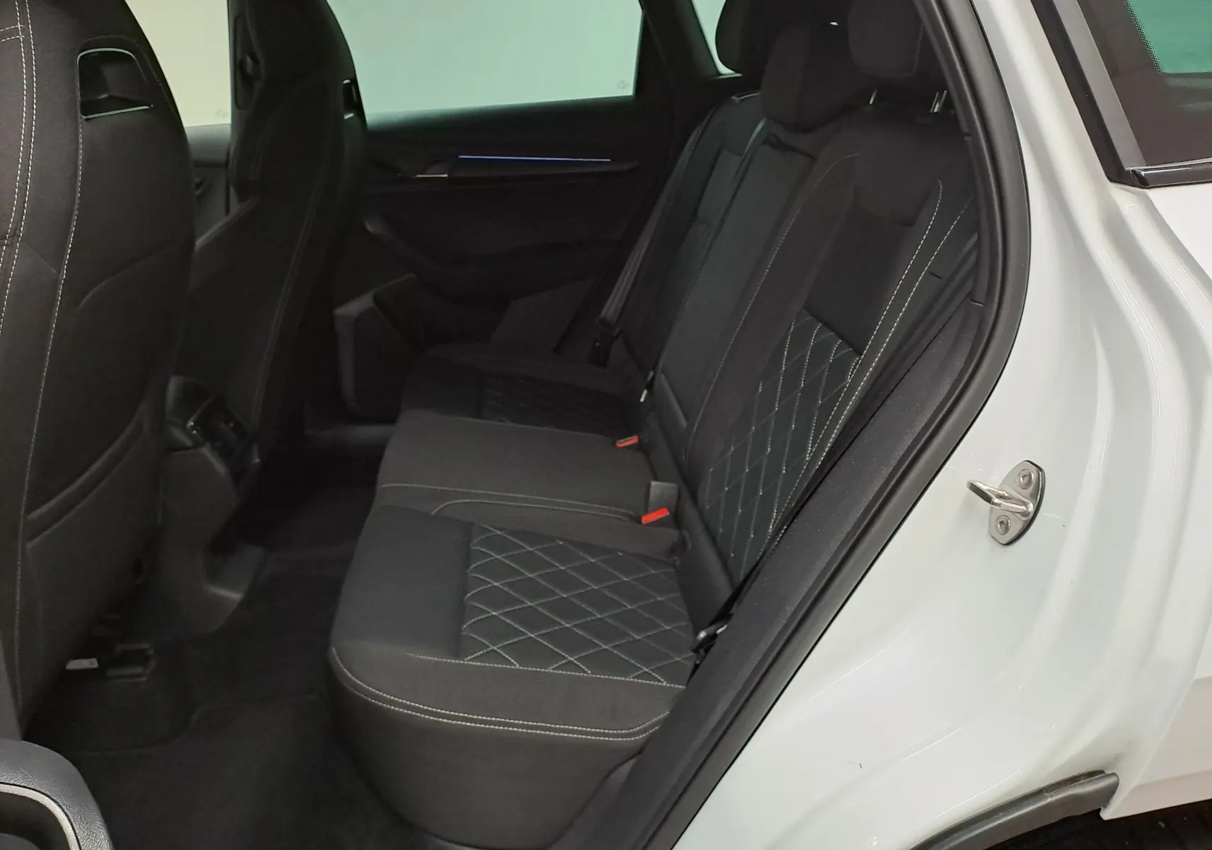 Vue intérieure côté droit sur les sièges arrière noirs avec surpiqûres en losange du Skoda Karoq Blanc Lune 2022 Sportline.