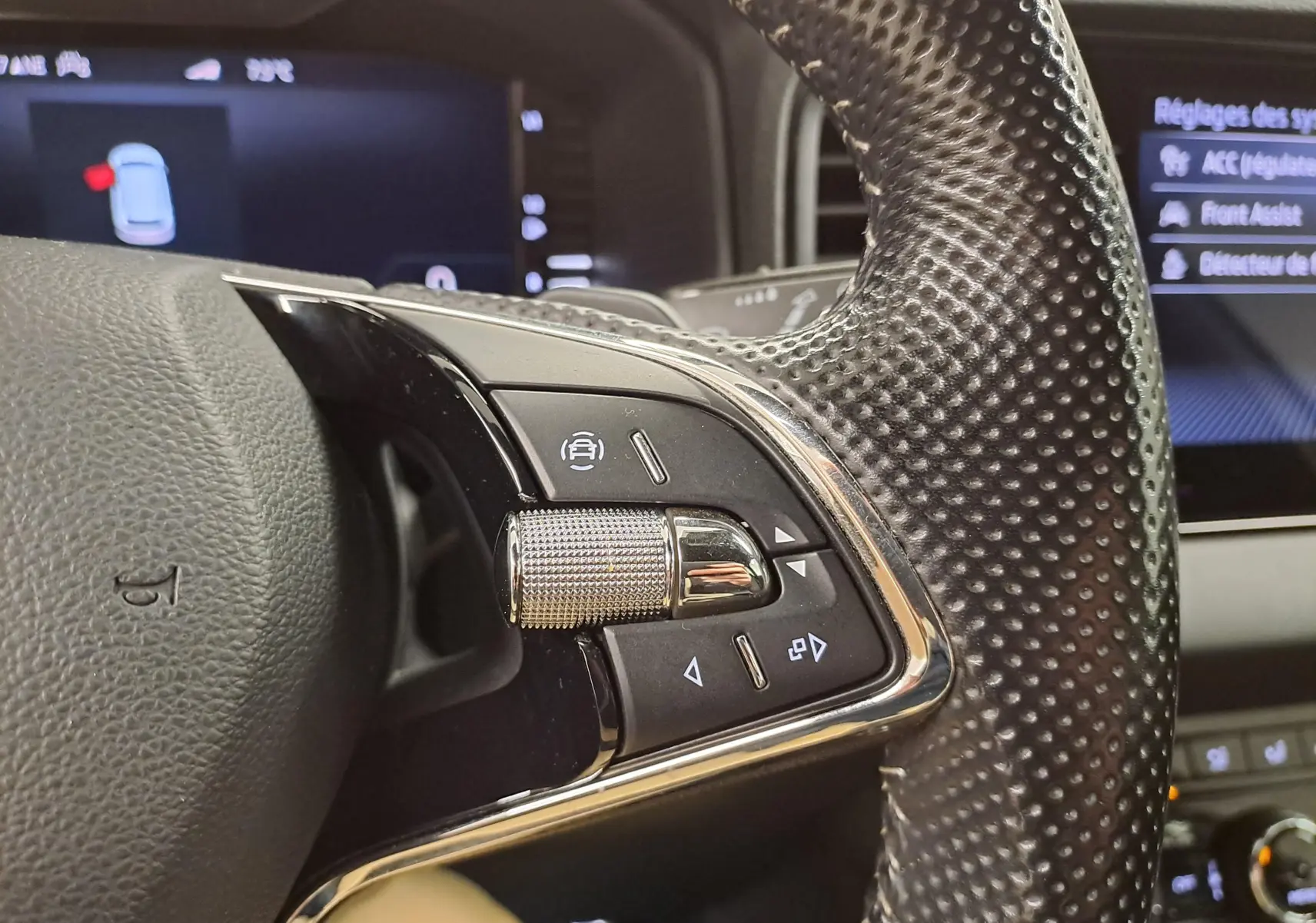 Gros plan sur les commandes au volant perforé du Skoda Karoq 2.0 TDI 116 DSG7 Sportline 2022 en Blanc Lune.