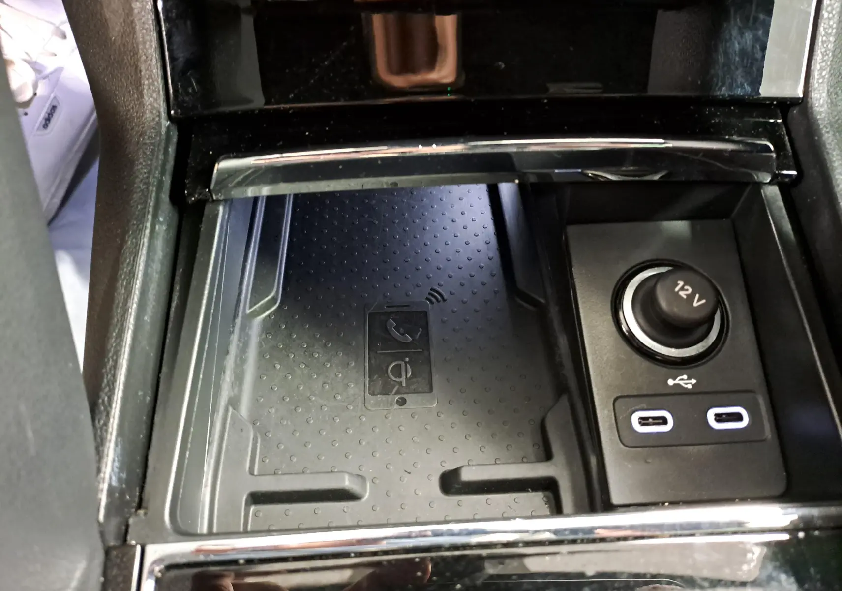Gros plan sur la console centrale du Skoda Karoq 2022, montrant un chargeur sans fil, prise 12V et ports USB.