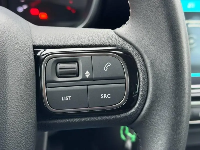 Gros plan sur les commandes audio au volant cuir de la Citroën C3 Aircross blanc Banquise, côté droit.