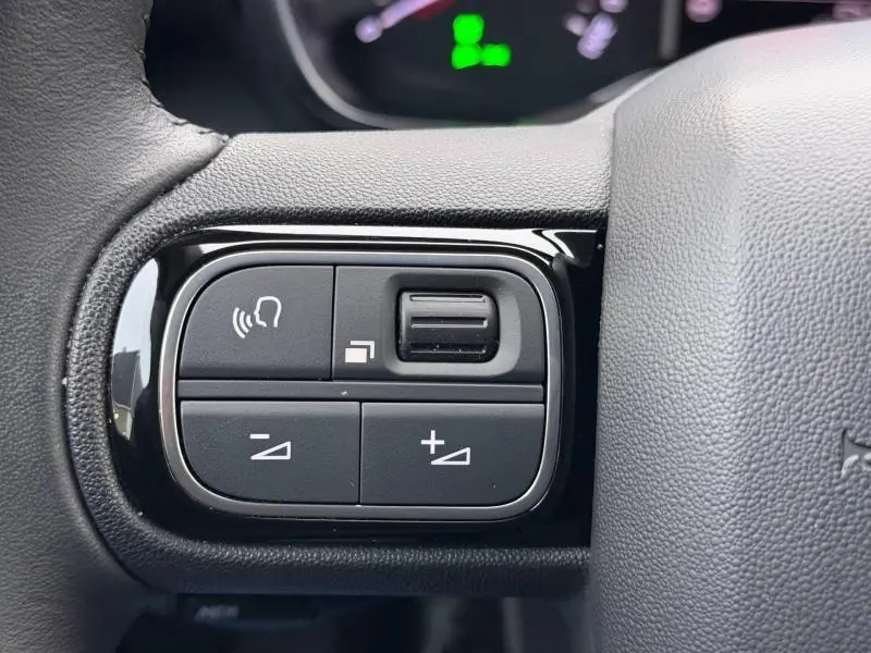 Gros plan sur les commandes audio au volant cuir du Citroën C3 Aircross blanc Banquise 2024.