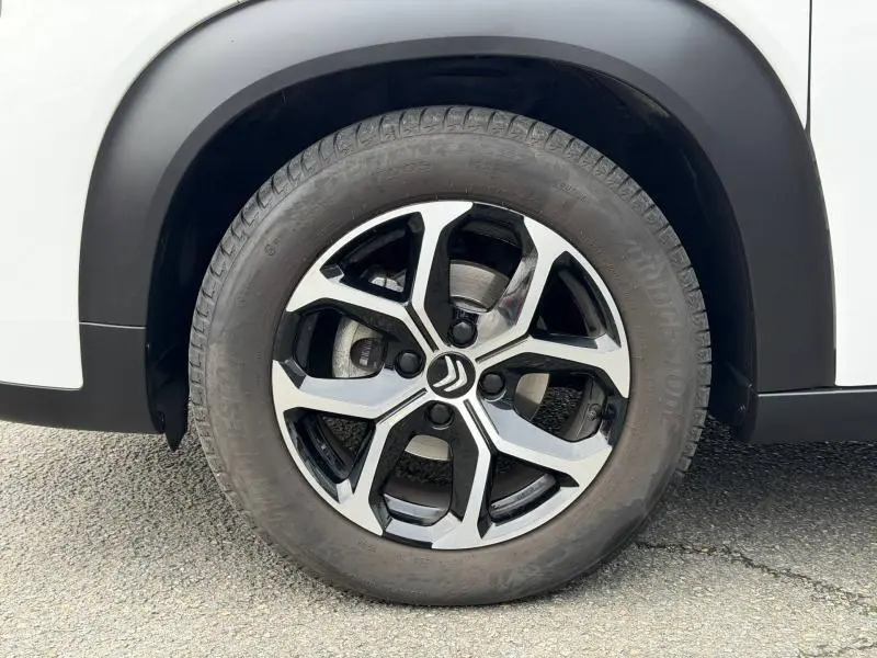 Gros plan sur la roue avant droite avec jante alu bicolore du Citroën C3 Aircross blanc Banquise.