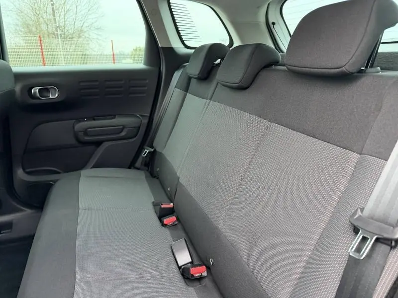 Vue latérale intérieure montrant la banquette arrière en tissu gris du Citroën C3 Aircross 2024 Blanc Banquise.