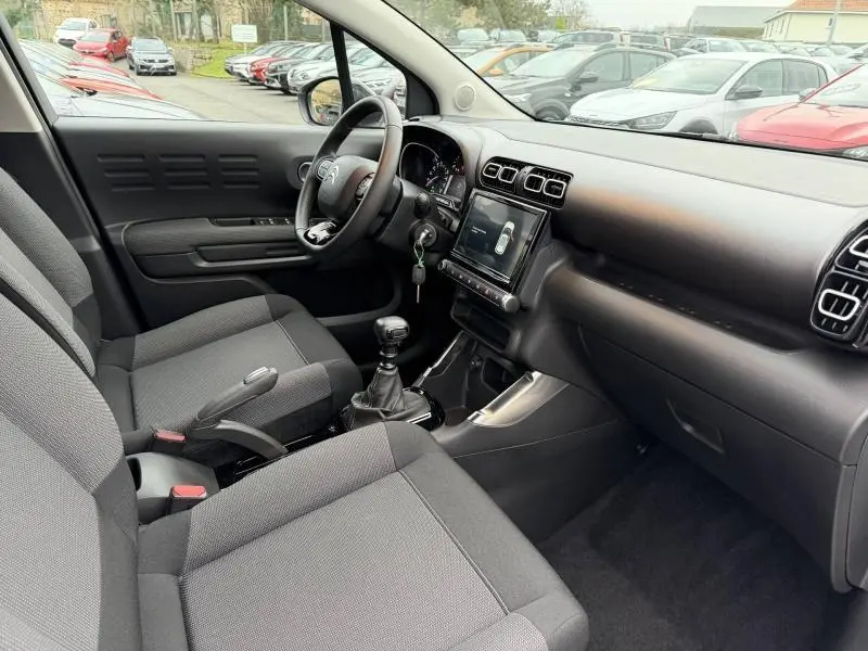 Intérieur côté conducteur du Citroën C3 Aircross 2024, volant cuir, tableau de bord noir avec écran tactile central.