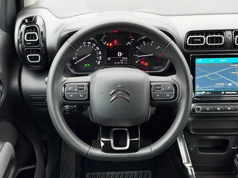 Vue frontale du volant cuir noir de la Citroën C3 Aircross 2024 avec tableau de bord et écran tactile affichant la navigation.