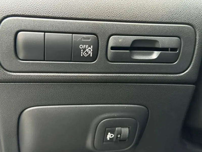 Détail intérieur montrant les commandes noires de réglage des aides à la conduite sur tableau de bord du Citroën C3 Aircross blanc.