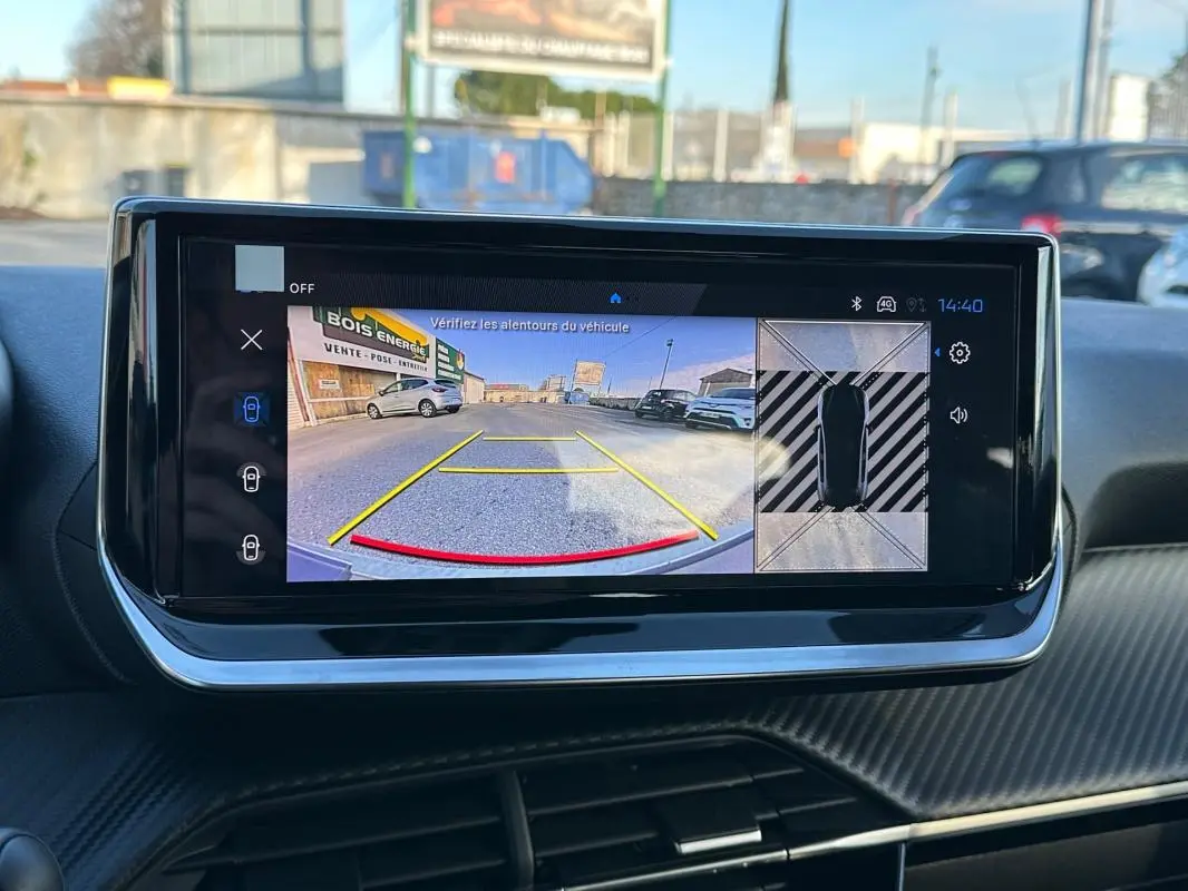Écran tactile intérieur montrant la caméra de recul et la vue 360° du Peugeot 208 blanc, version Hybrid 110 Allure.