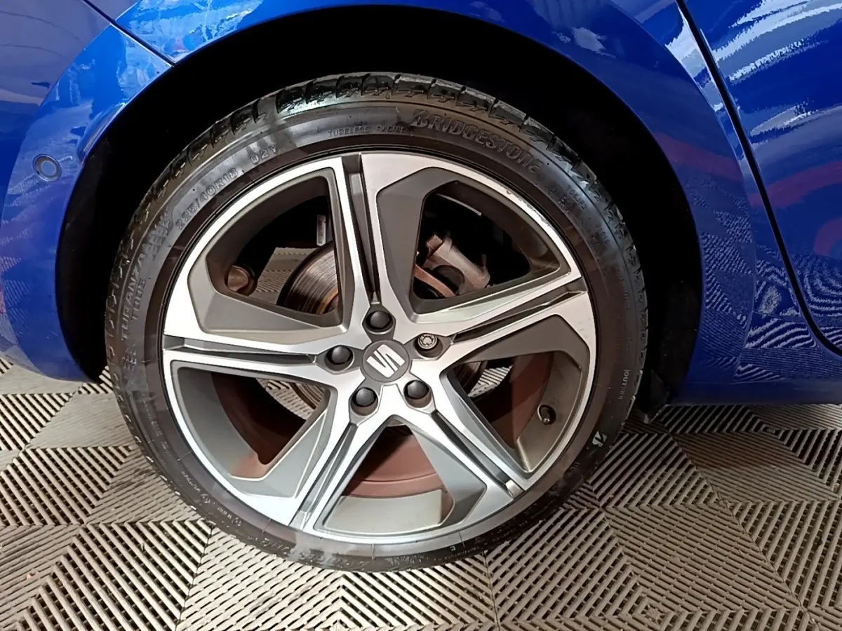 Gros plan sur la roue avant droite d'une SEAT Leon bleu 2021 avec jante alliage cinq branches et logo central.
