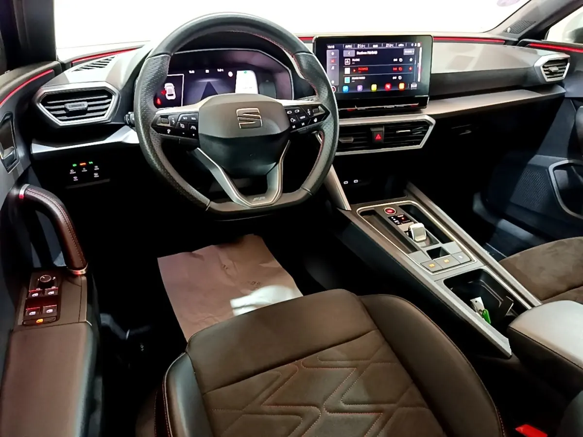 Vue intérieure avant droite du tableau de bord et volant cuir alu du SEAT Leon 1.5 eTSI bleu avec écran tactile et console centrale.