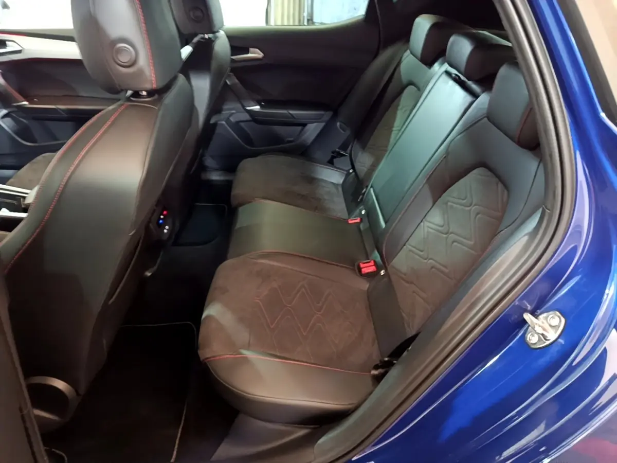 Vue intérieure côté droit sur la banquette arrière en cuir noir avec surpiqûres rouges d’un SEAT Leon bleu 2021.