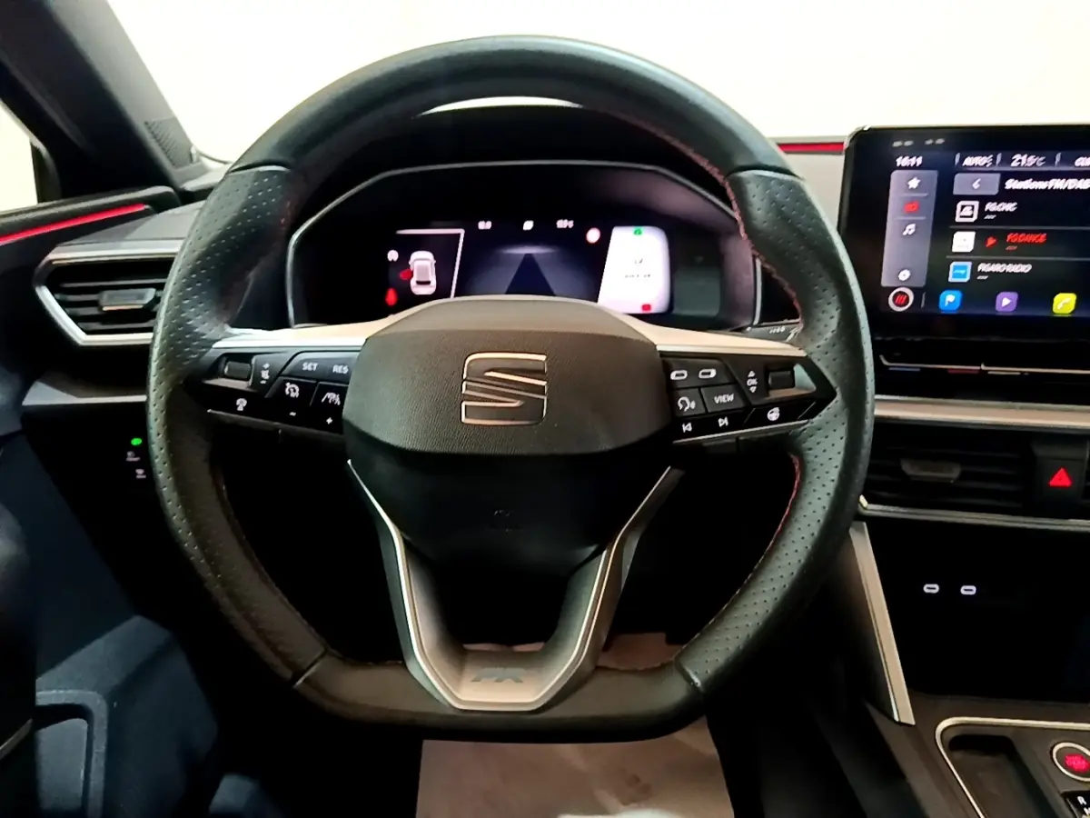 Vue frontale du volant cuir perforé noir de la SEAT LEON 1.5 eTSI avec tableau de bord numérique et écran tactile.