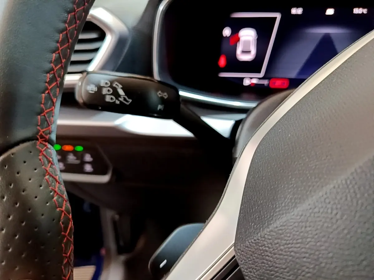 Gros plan sur le volant cuir noir avec surpiqûres rouges et le tableau de bord numérique du SEAT Leon 1.5 eTSI 2021.