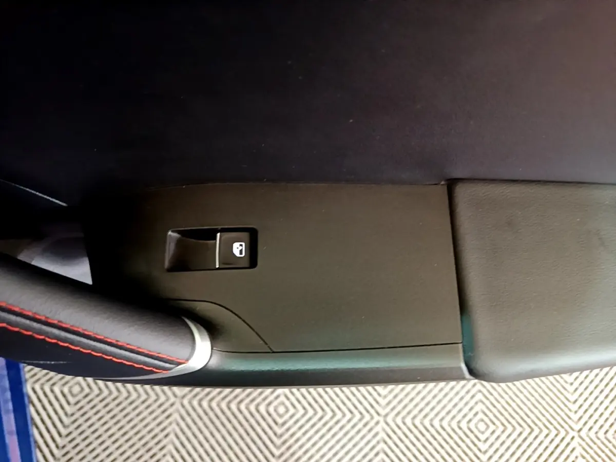 Détail de la poignée de porte intérieure côté gauche avec bouton de verrouillage, sur SEAT Leon bleu 2021.