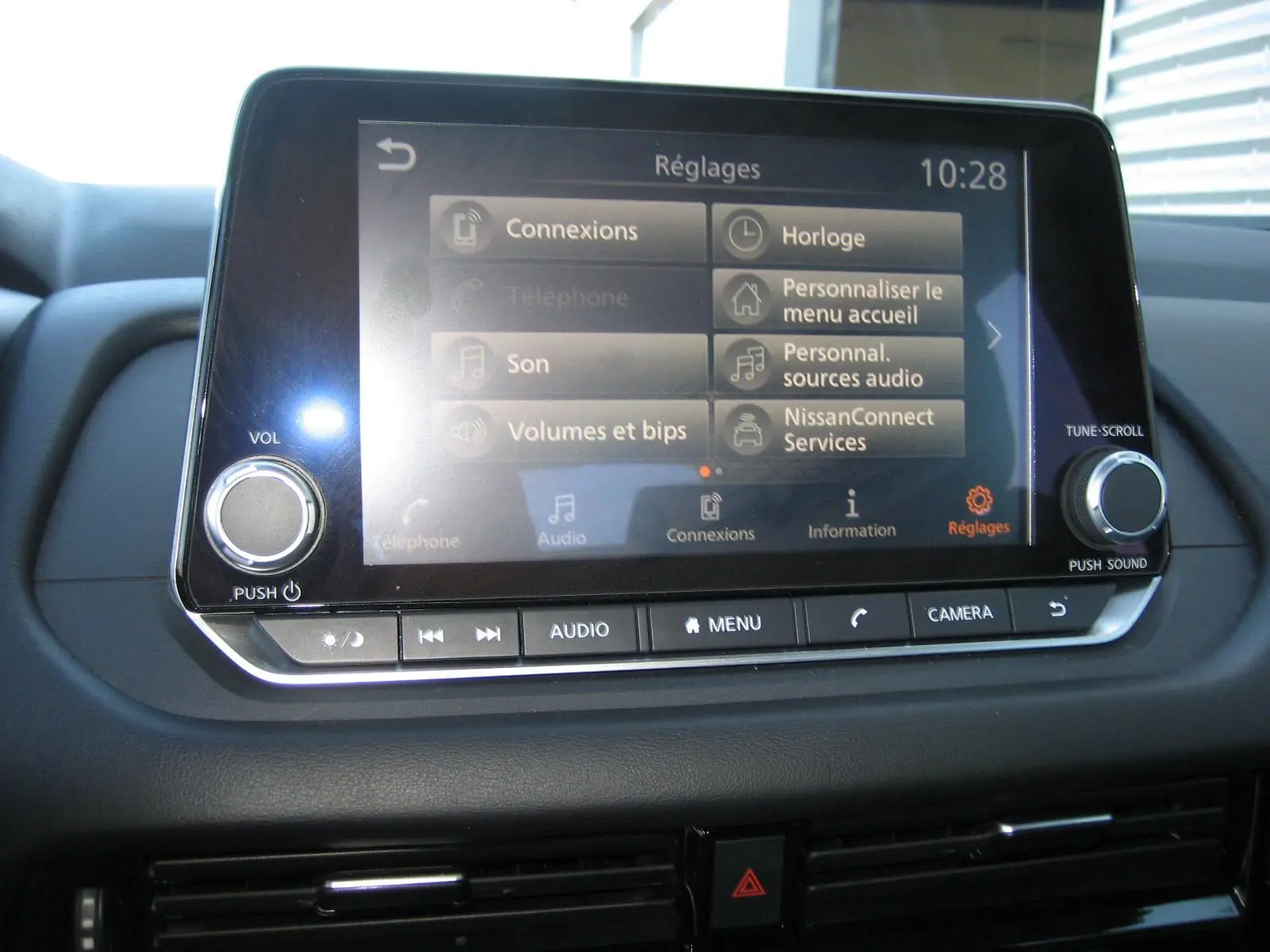 Écran tactile central du Nissan Qashqai 2024 affichant le menu réglages, avec commandes audio et caméra visibles.