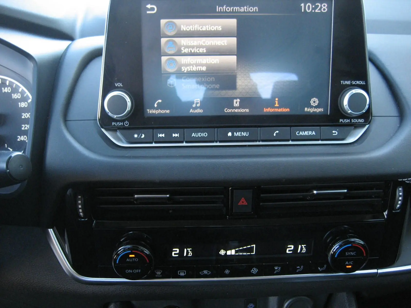 Vue rapprochée de la console centrale du Nissan Qashqai blanc nacré 2024, affichant l’écran tactile et la climatisation digitale.