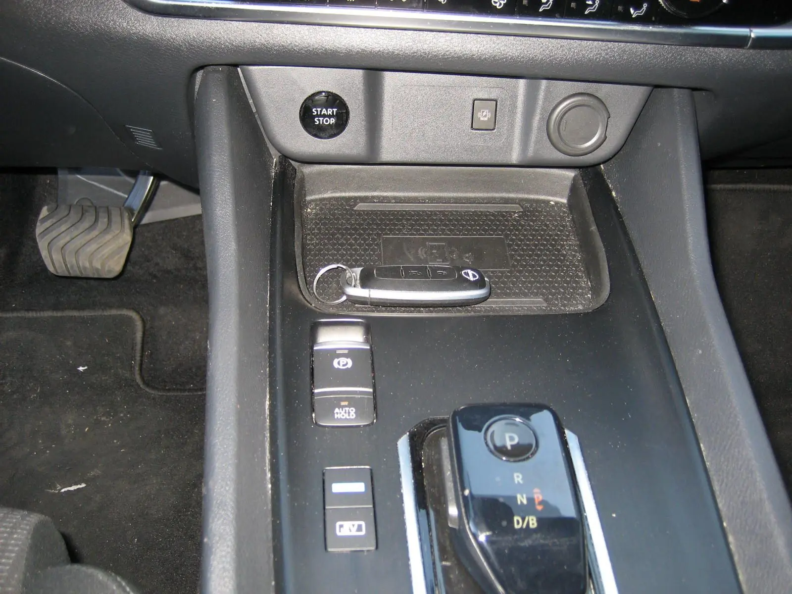 Vue rapprochée de la console centrale noire du Nissan Qashqai blanc nacré, avec clé, bouton start/stop et levier de vitesse automatique.