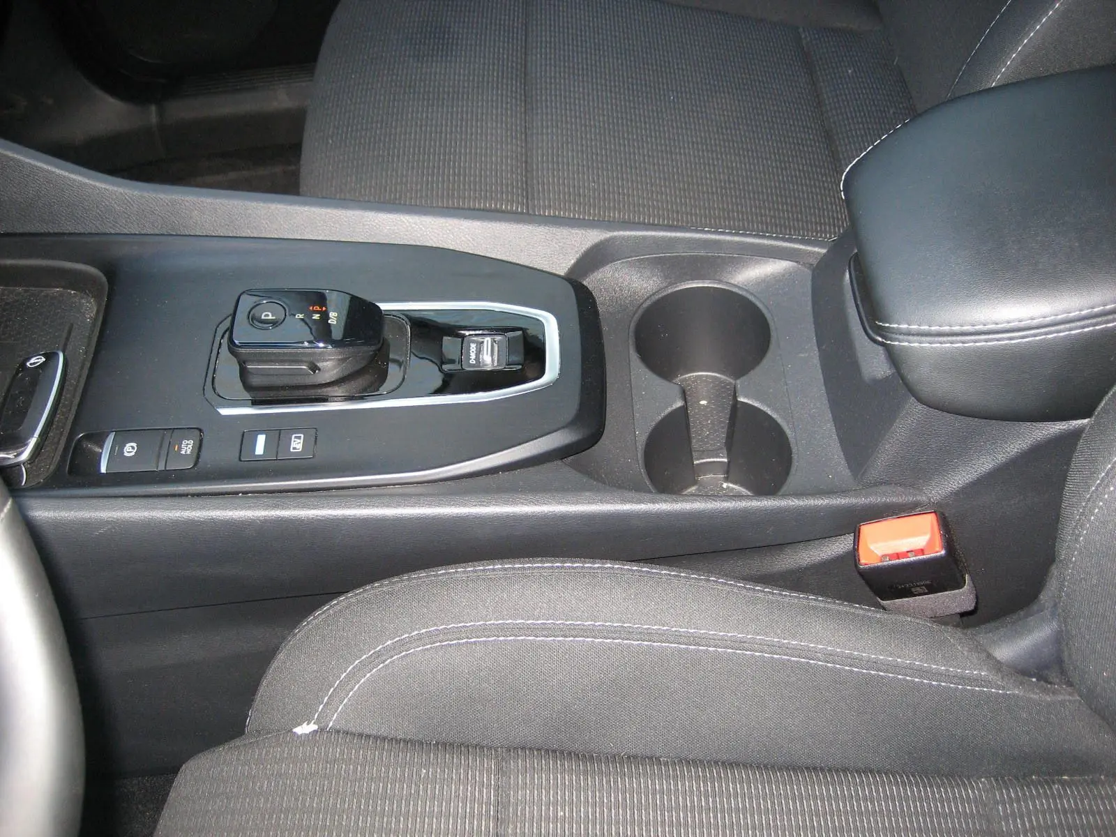 Vue rapprochée de la console centrale noire du Nissan Qashqai 2024 avec levier de vitesse automatique et porte-gobelets.