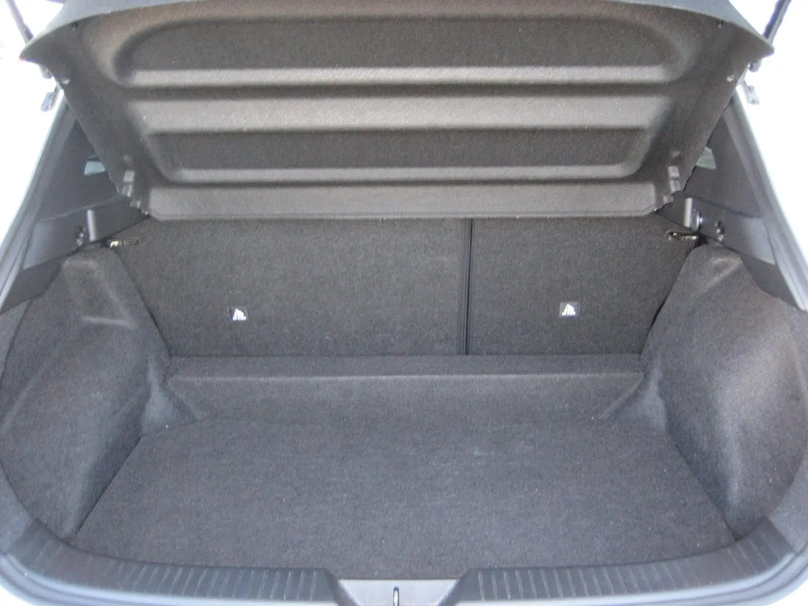 Coffre ouvert d’un Nissan Qashqai blanc nacré 2024, montrant un espace de chargement vide et tapissé de tissu gris.