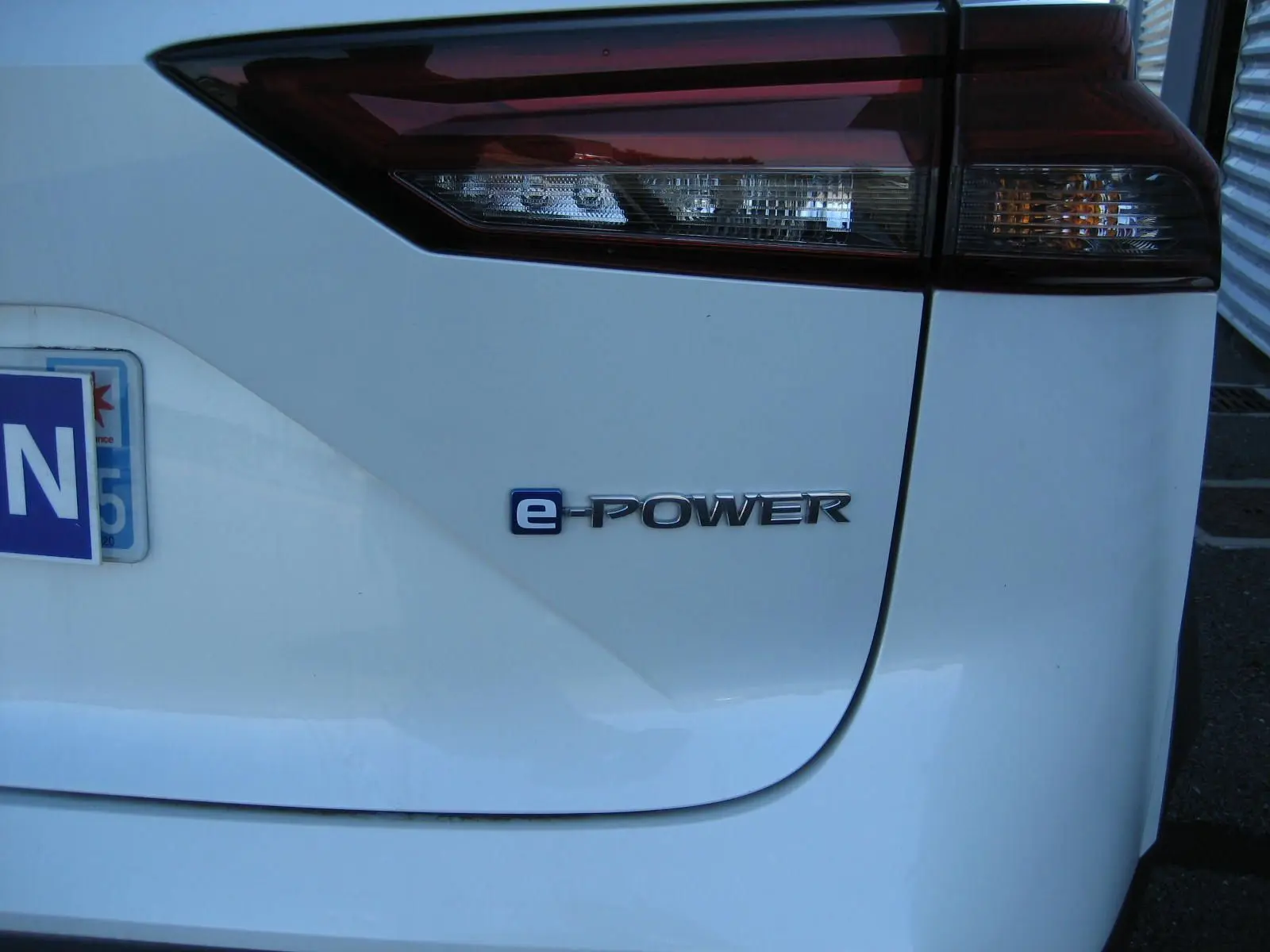 Gros plan sur le feu arrière droit et le logo e-POWER d’un Nissan Qashqai blanc nacré de 2024.