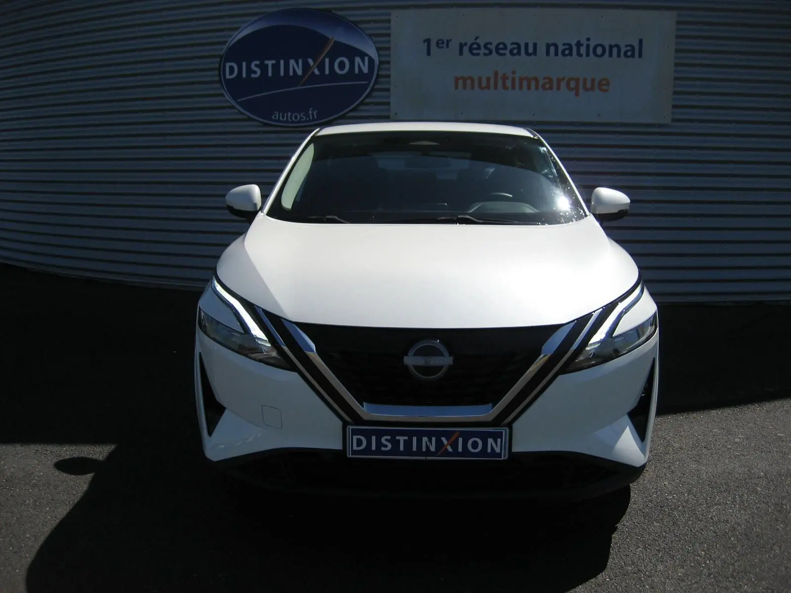 Vue frontale d'un Nissan Qashqai blanc nacré 2024 avec calandre noire et phares LED distinctifs.