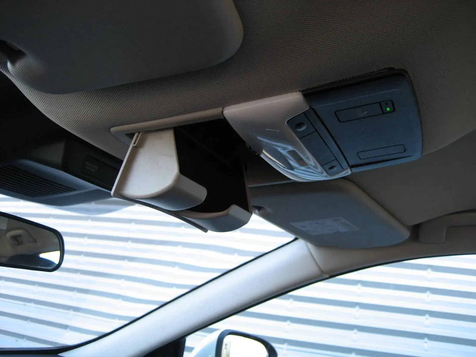 Vue intérieure du plafond du Nissan Qashqai blanc nacré 2024, avec rangement lunettes ouvert et commandes intégrées.