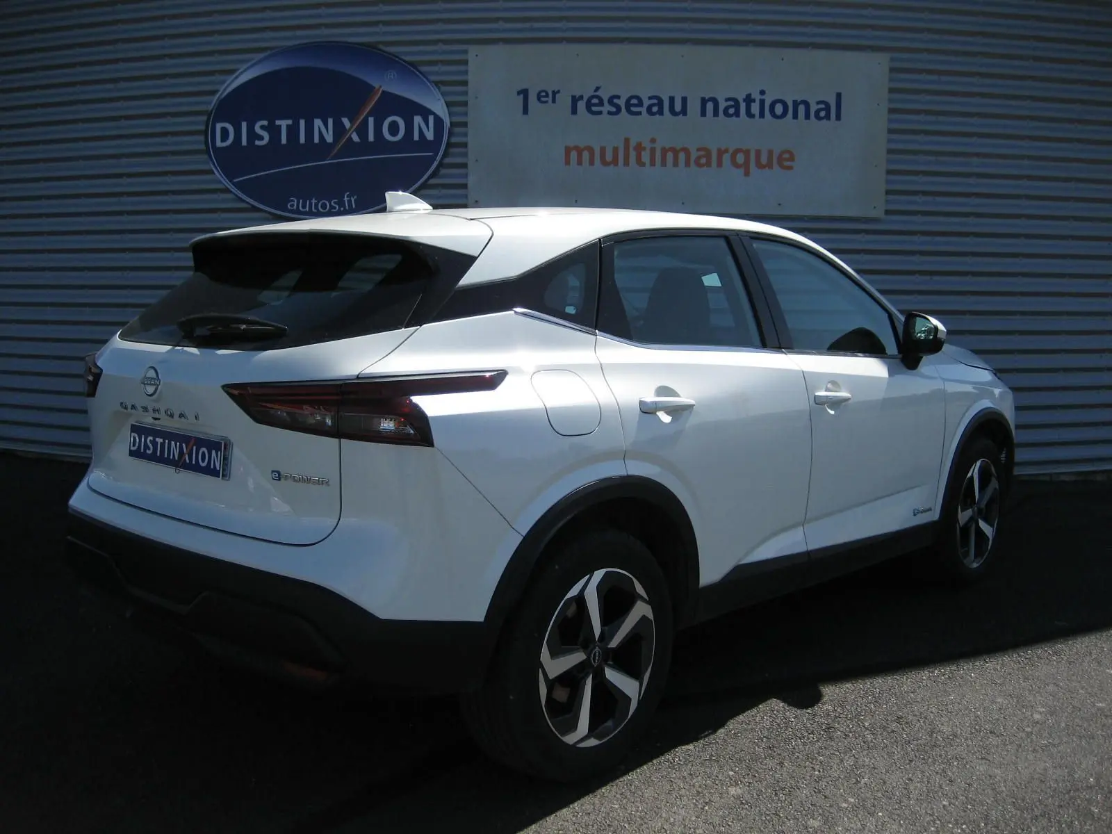 Vue 3/4 arrière droite du Nissan Qashqai blanc nacré E-POWER 2024 avec jantes bi-ton et feux LED distinctifs.