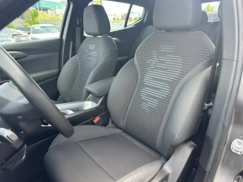Vue intérieure côté conducteur de l'Alfa Romeo Tonale 2025, sièges tissu noir avec logo Alfa Romeo brodé sur appuie-tête.