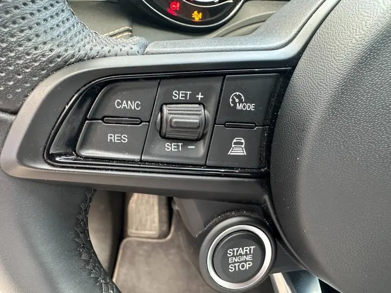 Gros plan sur les commandes au volant noir et bouton Start/Stop dans l’habitacle de l’Alfa Romeo Tonale gris Vesuvio.