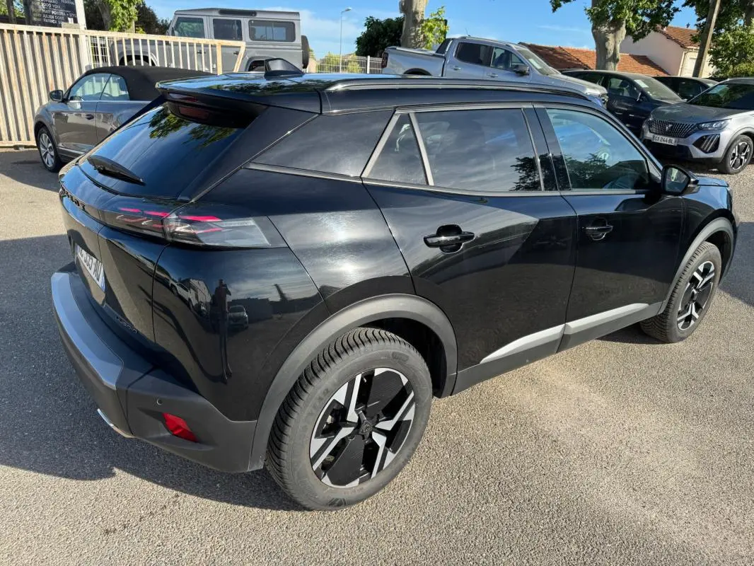Peugeot 2008 Hybrid noir vue 3/4 arrière droit, avec barres de toit et jantes alliage 17 pouces visibles.