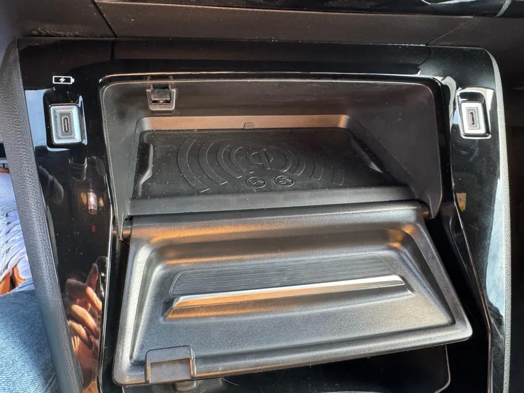Détail de la console centrale noire du Peugeot 2008 Hybrid 136 avec compartiment de rangement et chargeur sans fil.