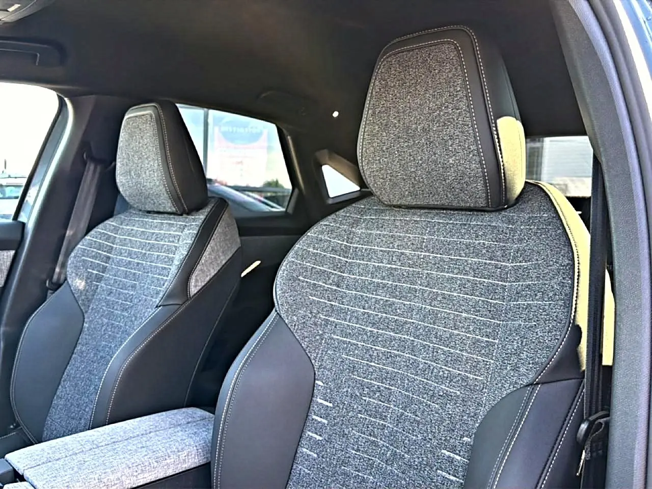 Gros plan sur les sièges avant en tissu gris et cuir noir du Peugeot 3008 1.2 hybrid 145 allure e-dcs6 bleu 2025.