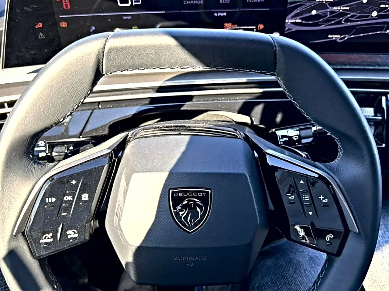 Vue rapprochée du volant cuir noir multifonction du Peugeot 3008 2025 avec logo lion central et commandes intégrées.