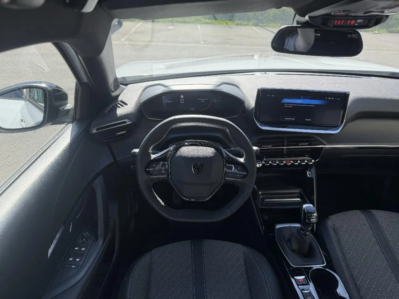 Vue intérieure du poste de conduite du Peugeot 2008 blanc okenite 2024, avec volant compact et boîte manuelle.
