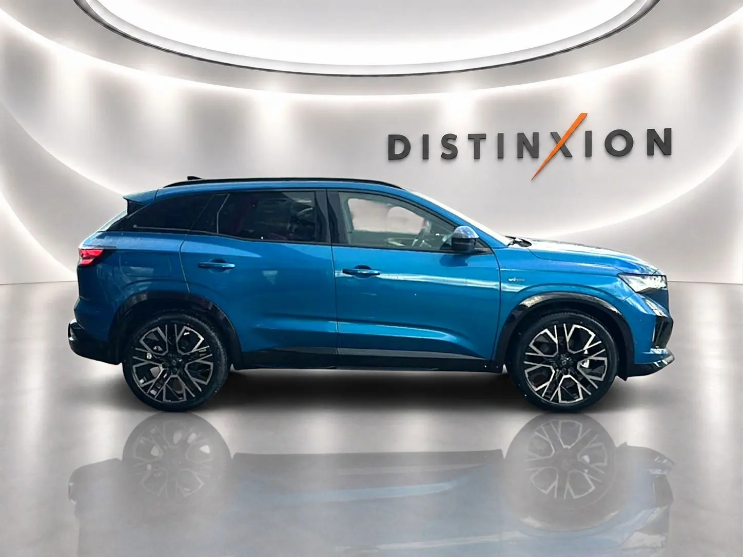 Vue de profil côté gauche du Renault Austral bleu outremer avec jantes alliage et toit noir dans un showroom lumineux.