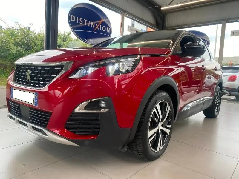 Peugeot 3008 rouge vue 3/4 avant droit en showroom, avec calandre et phares LED distinctifs allumés.