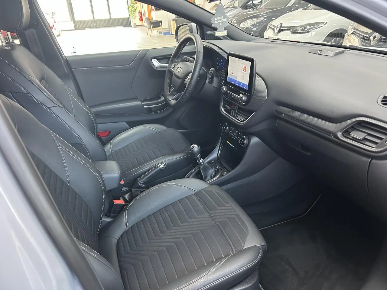 Intérieur avant droit de la Ford Puma 2023 gris, sièges noirs mixte cuir-tissu et tableau de bord avec écran tactile central.