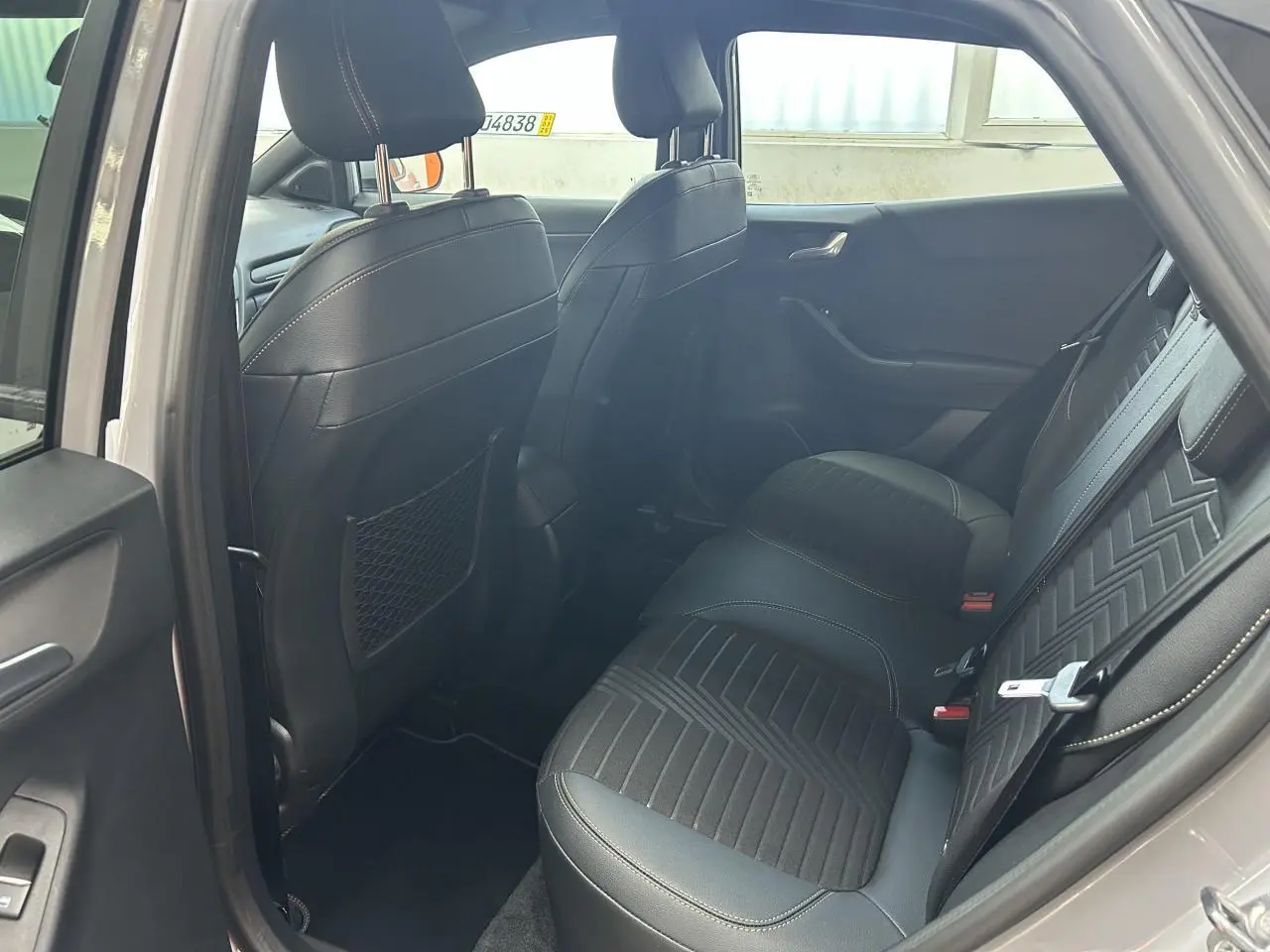 Vue intérieure arrière côté gauche du Ford Puma gris 2023, sièges arrière en cuir et tissu noir avec surpiqûres.