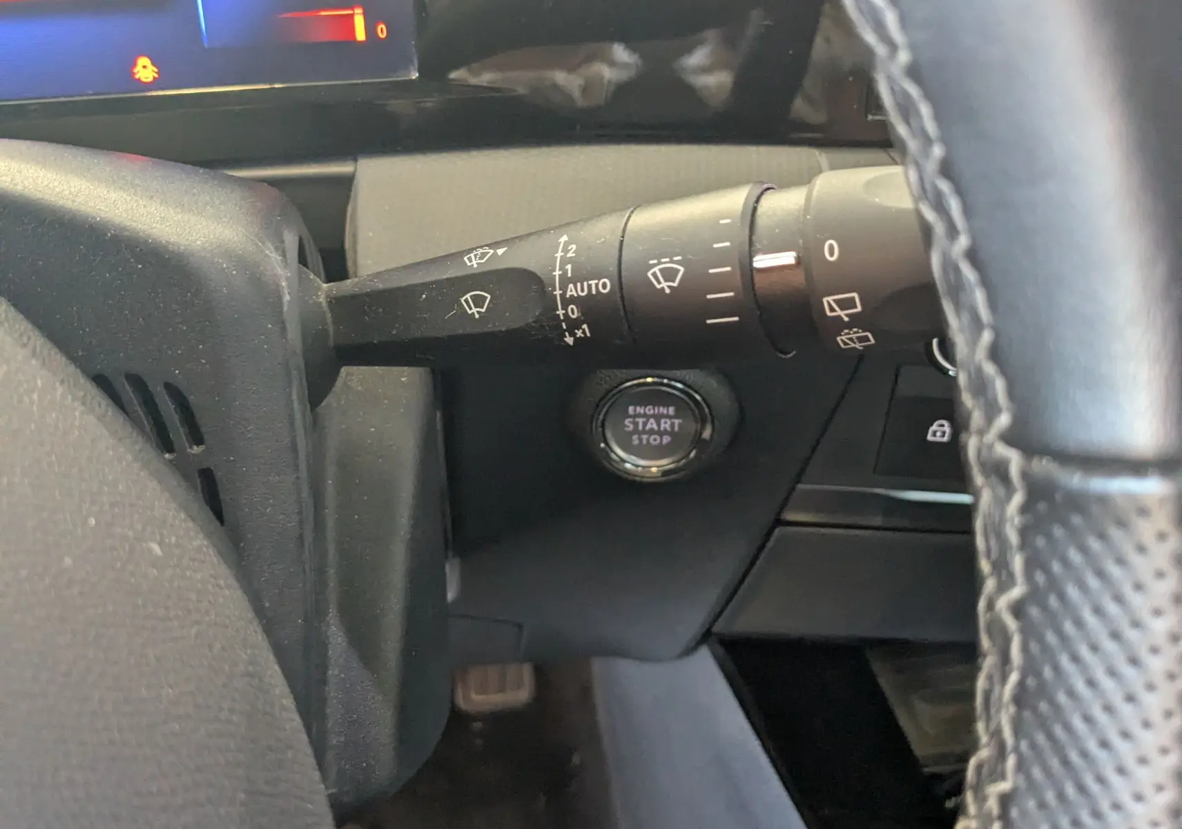 Vue intérieure côté gauche du volant de l'Opel Astra 1.5D 130ch avec bouton start/stop et commandes essuie-glace visibles.