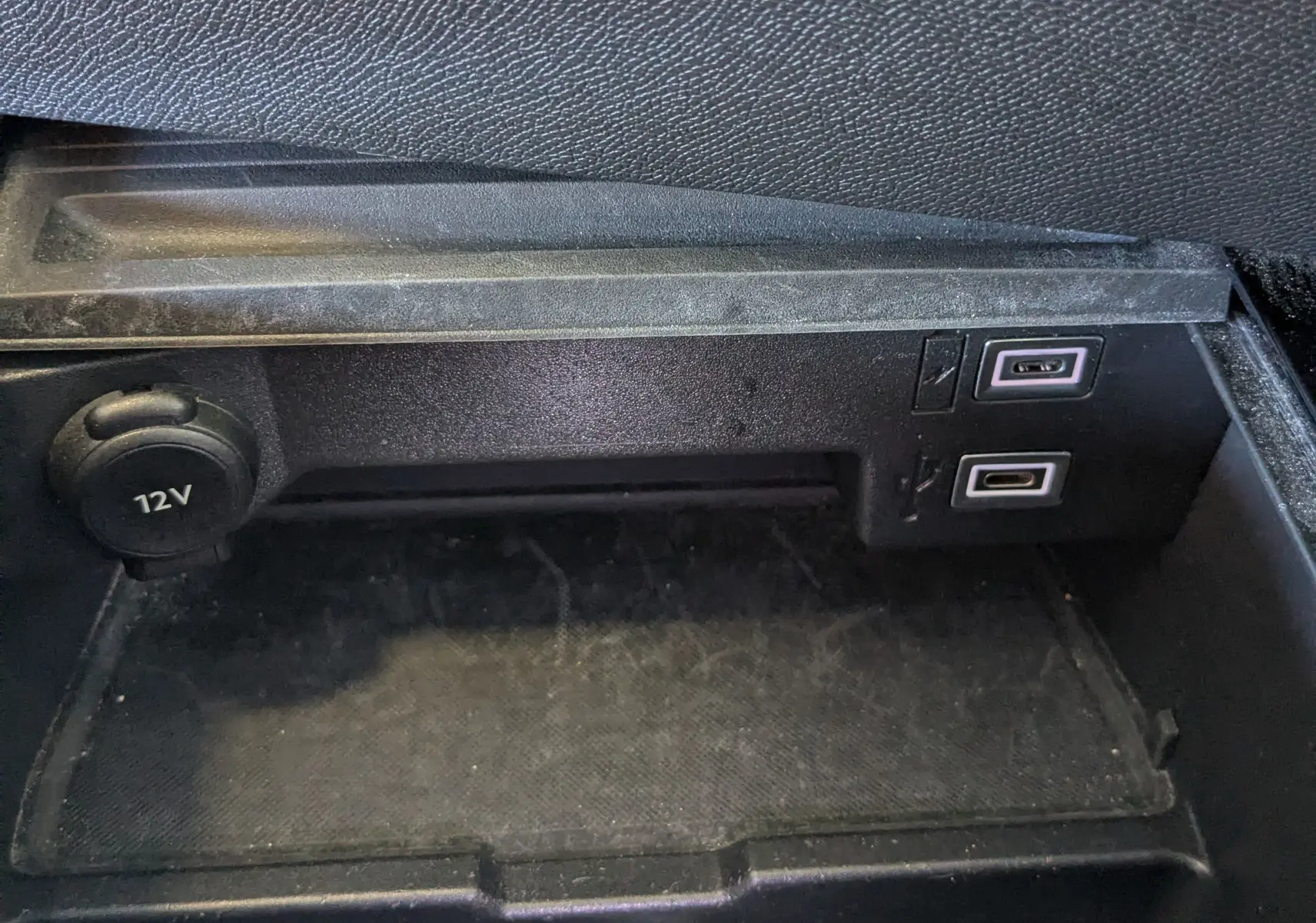 Gros plan sur la prise 12V et ports USB dans le rangement intérieur d'une Opel Astra bleu 2022 finition Elegance.