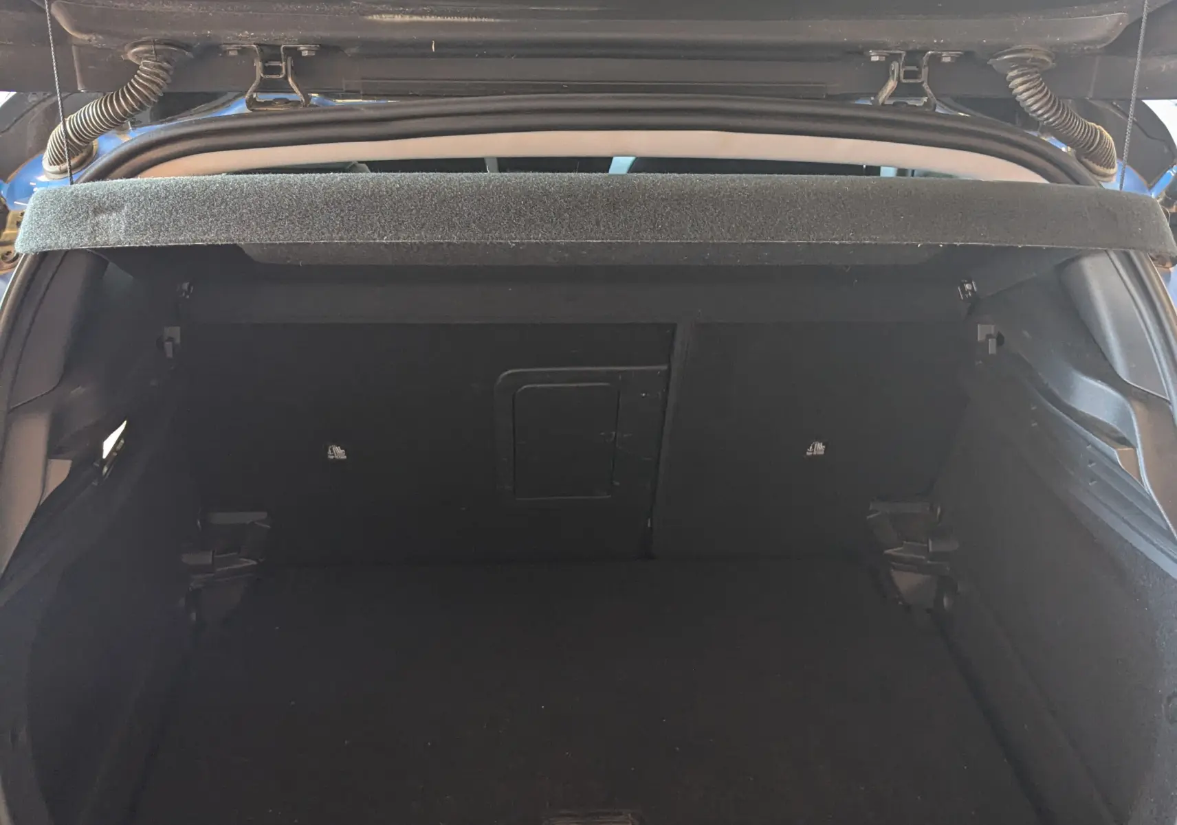 Coffre ouvert vu de l'arrière d'une Opel Astra 1.5D bleu 2022, montrant l'espace de chargement vide et la plage arrière.