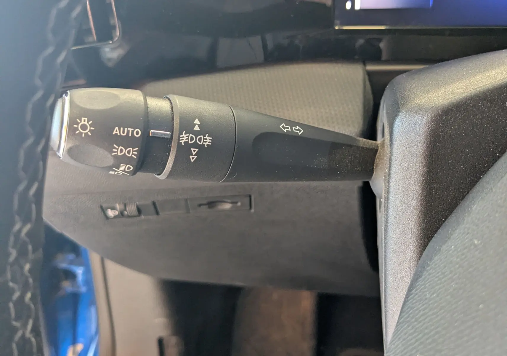 Gros plan sur la commande des feux à gauche du volant dans l'habitacle d'une Opel Astra bleu 2022.
