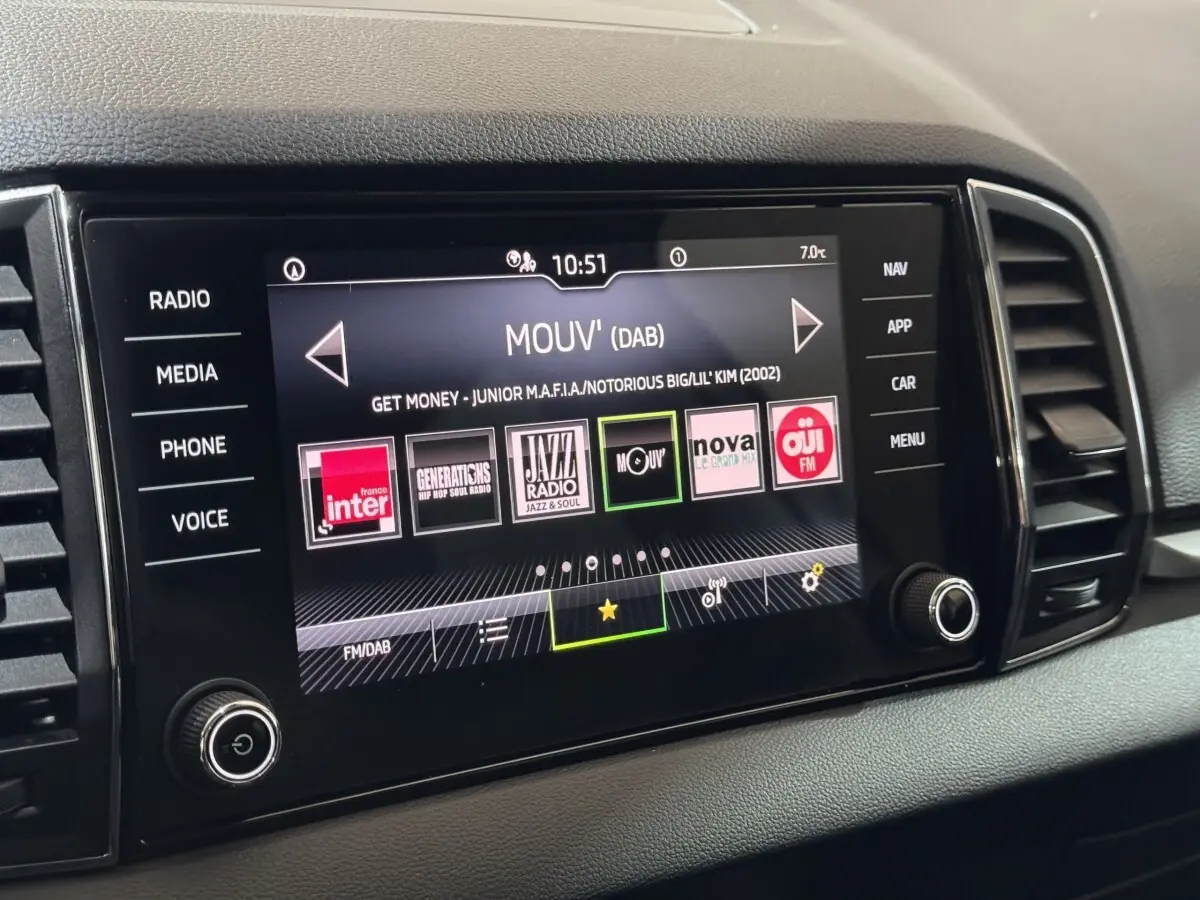 Écran tactile central du tableau de bord du Skoda Karoq blanc, affichant les stations radio numériques.
