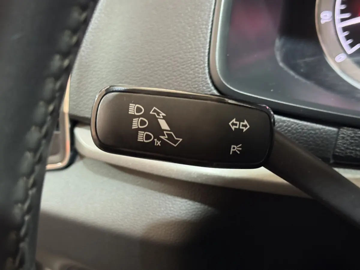 Gros plan sur la manette de clignotants noire à gauche du volant dans l'habitacle du Skoda Karoq blanc 2021.